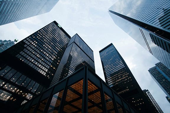 Tall glass skyscrapers in a financial district under a cloudy sky.